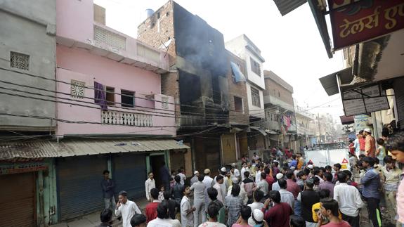 Varias personas observan el edificio arrasado por el fuego en Nueva Delhi (India).
