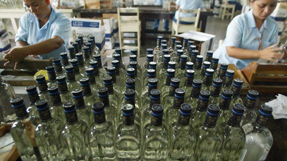 Trabajadores etiquetan botellas de ron. 