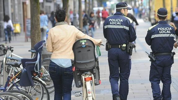 Una ciclista pasa bici en mano junto a unos policías en Vitoria