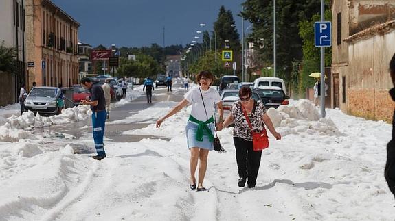 Varias personas caminan sobre el granizo acumulado.