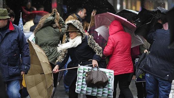 Una mujer sujeta su paraguas para portegerse de la lluvia en Bilbao.