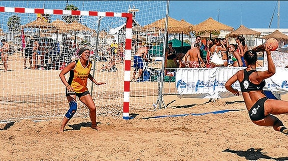 Una jugadora con la indumentaria oficial dispara un balón contra una portera vestida con la equipación tradicional