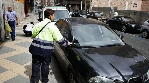 Controladora de la zona azul revisando el ticket de un vehículo. 