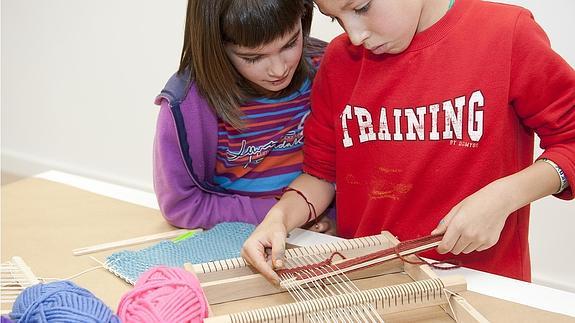 Dos niños tejen en un telar en una edición anterior de los talleres.