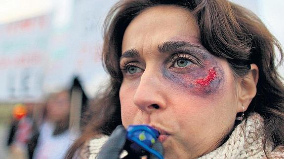 Una mujer, maquillada con un moretón, en una protesta contra el maltrato machista.