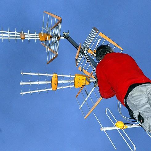 Un operario trabajando en la antena colectiva de una vivienda.