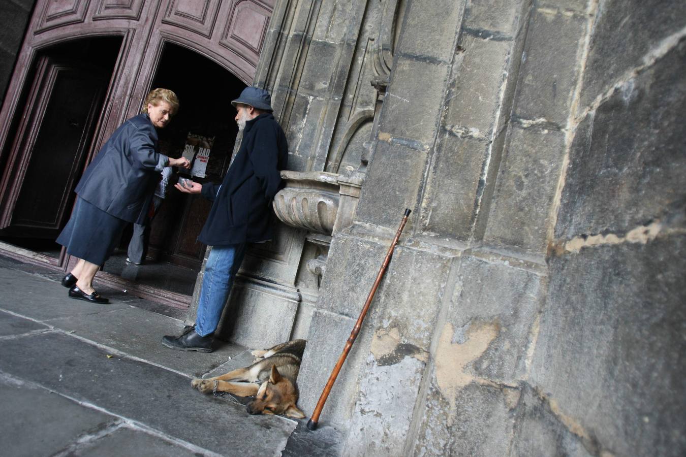 Una persona pide limosna a la puerta de una iglesia 