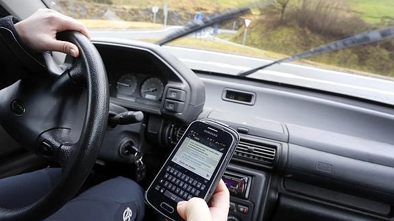 Un joven escribe en su 'smartphone' un mensaje de Whatsapp mientras conduce.