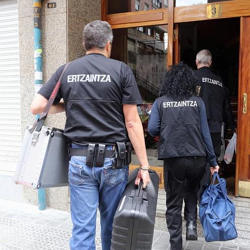 Especialistas de la Ertzaintza entran en el piso. 