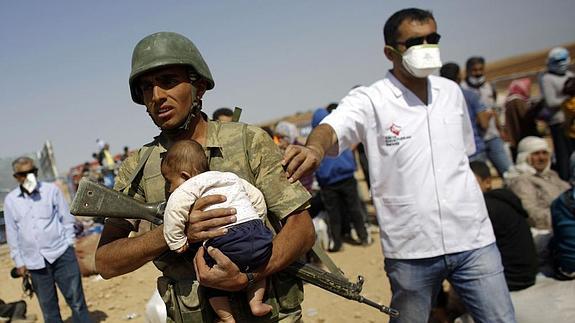 Un soldado turco lleva en brazos a un bebé kurdo en el campamento de Suruc. 