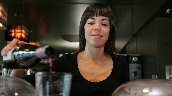 Una camarera sirve una consumición en un bar.