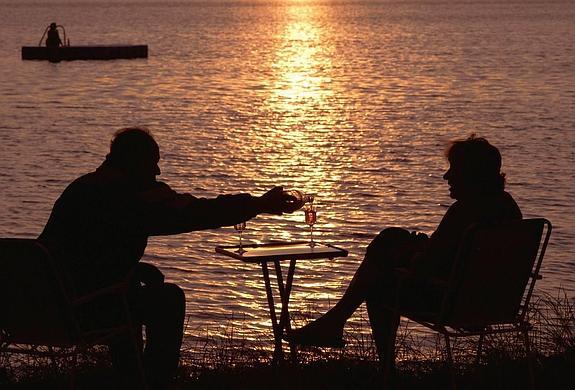 Una pareja disfruta de una copa de vino al atardecer.