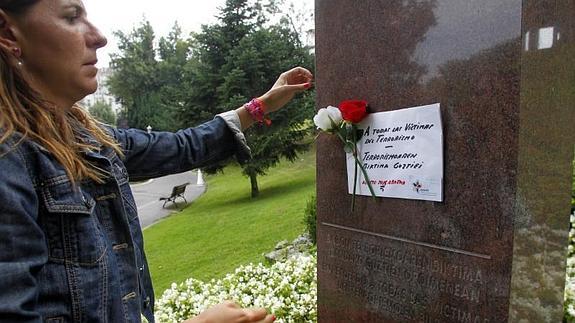La colaboradora de Covite Ana Berlanga, coloca dos rosas y un cartel en el monolito a las víctimas del terrorismo atacado hoy.  