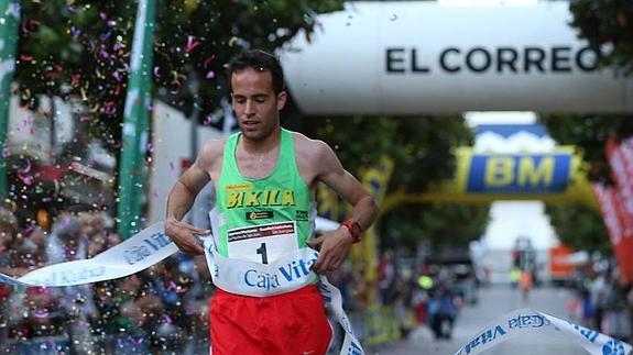 Iván Fernández cruza victorioso la línea de meta en una carrera urbana. 