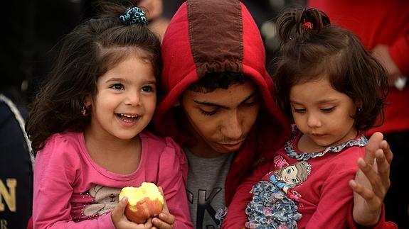 Unos refugiados de corta edad esperan a sus documentos para cruzar la frontera entre Macedonia y Grecia. 