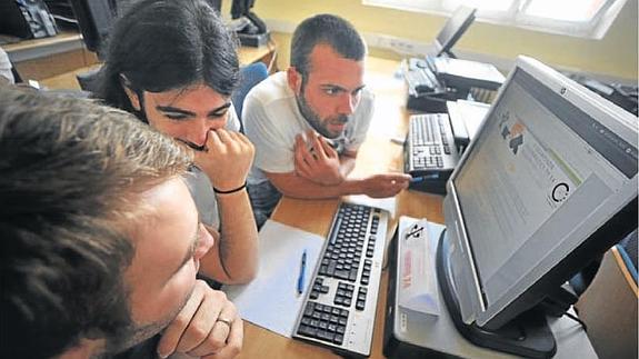 Tres jóvenes realizan una consulta en el ordenador en su puesto de trabajo