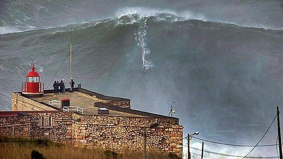 Surfista Nazareko olatu erraldoiarean gainean dagoen bitartean, zaleek ikuskizunaz gozaten dute.