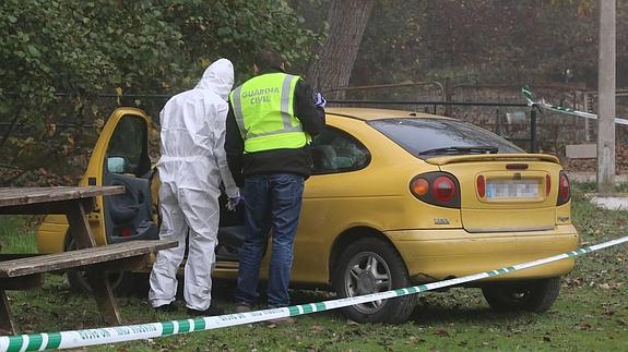 Dos agentes de la Guardia Civil recogen evidencias en el coche de la víctima, cerca de donde fue encontrado malherido.