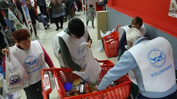 Varios voluntarios recogen los alimentos donados por los clientes de un supermercado.