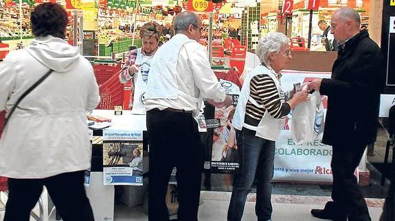 Un cliente dona a los voluntarios parte de su compra en un centro comercial de Logroño. 