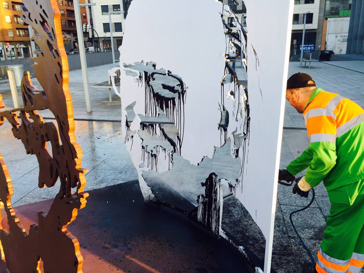 Un operario limpia los daños causados en la escultura en homenaje al alcalde Iñaki Azkuna situada en la plaza de la clínica IMQ.