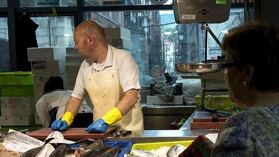 Un pescadero atiende a una clienta en el mercado de la Ribera.