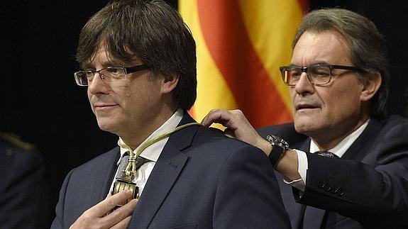 Carles Puigdemont recibe de su predecesor Artur Más la medalla representativa del cargo de presidente de Cataluña.