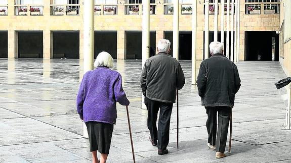 Tres ancianos se resguardan de la lluvia en los soportales de la Plaza del Ayuntamiento.