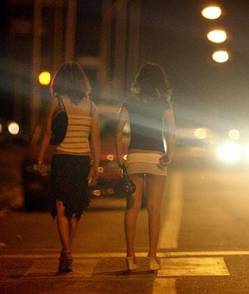 Dos prostitutas, ajenas a la información, espetran clientes en la calle. 