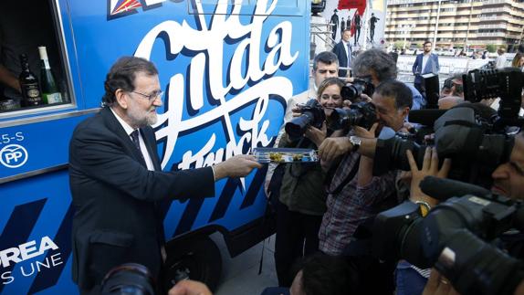 El presidente del Gobierno en funciones, Mariano Rajoy, ofrece pintxos en el 'Gilda Truck', durante un paseo hoy por las calles de San Sebastián.