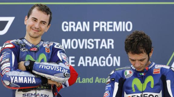 Jorge Lorenzo esboza media sonrisa junto al cabizbajo Valentino Rossi en un podio del Mundial de MotoGP. 