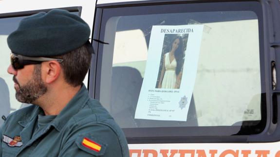 Un efectivo de la Guardia Civil junto al cartel de la joven Diana Quer.