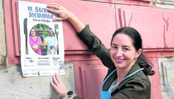Elena Arzak con el cartel de la Comida Solidaria en la fachada del Ayuntamiento.