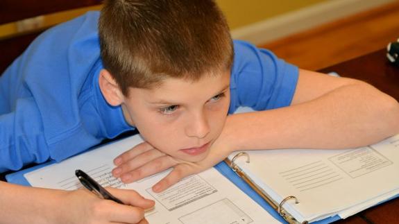 Un alumno se muestra distraído mientras hace los deberes en casa.