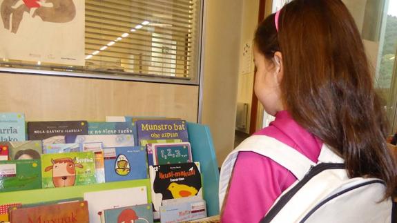Una niña observa el material en la biblioteca de Abusu.