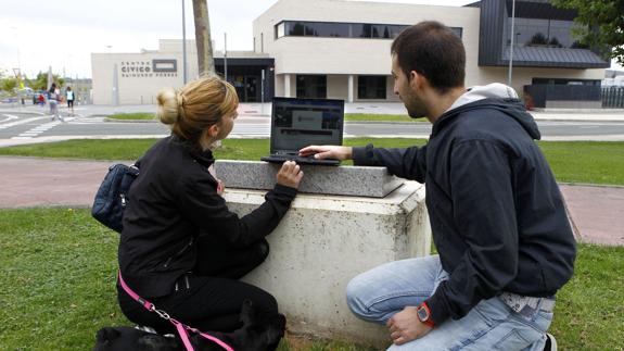 Dos personas consultan la web municipal junto al centro cívico. 