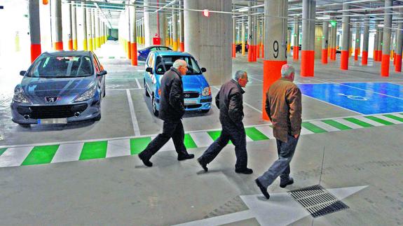 Tres hombres caminan por el interior del infrautilizado parking de la estación de autobuses. 