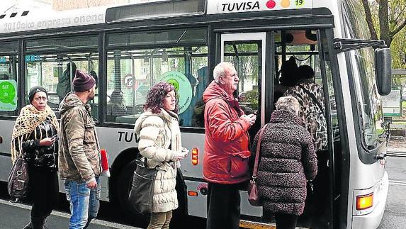 Viajeros hacen fila para subir a un autobús de Tuvisa.