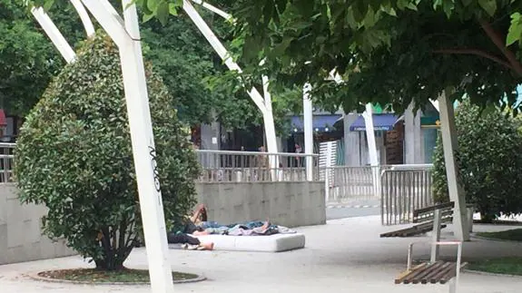 Unos jóvenes descansan en un colchón colocado en la plaza.
