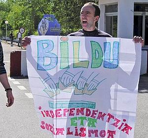 El etarra Ander Errandonea Arruti, con la pancarta de apoyo a Bildu, donde se lee el lema "Independentzia eta sozialismoa". /Efe