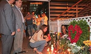 La madre de Mikel, acompañada de su marido, deposita una vela ante la foto de su hijo esta pasada medianoche en Portugalete. :: MITXEL ATRIO