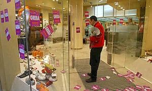 Mimebros de los piquetes colocan pegatinas en el escaparate de una tienda de Bilbao./E.C.