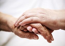 Un familiar coge la mano de un enfermo para reconfortarle./ Fotolia