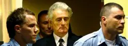 Radovan Karadzic llega a la sala del Tribunal de La Haya acompañado de varios guardianes para escuchar los cargos que pesan sobre él./ REUTERS