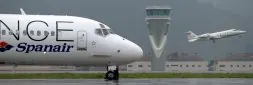 Un avión de Spanair toma posiciones en la pista del aeropuerto de Loiu mientras otra aeronave despega frente a la torre de control. / FERNANDO GÓMEZ