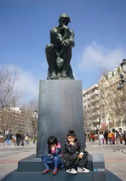 Dos niños posan con 'El Pensador' de Rodin en un céntrico parque de Granada. / EL CORREO