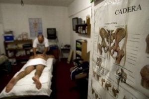 Un hombre da un masaje a un paciente en una consulta. / AP