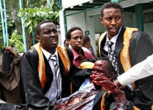 Estudiantes universitarios trasladan el cuerpo de una de las víctimas destrozada por la explosión. ::                             AFP