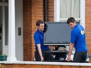 Dos jóvenes cargan con el televisor de la familia Cameron para trasladarlo a Downing Street. ::                             AFP