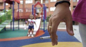 Una mujer vigila los juegos de su hija en un parque infantil mientras se fuma un pitillo.  ::                             FERNANDO GÓMEZ